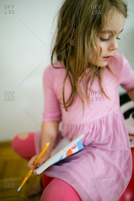 Girl in a pink dress writing in a notebook
