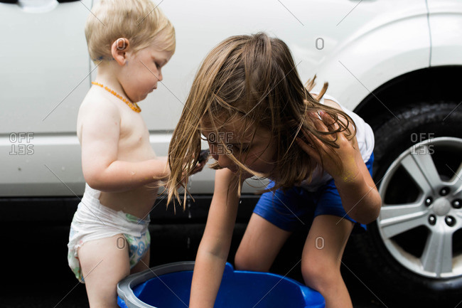 A girl and her brother wash a car together