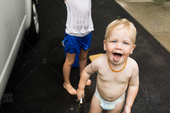 A toddler sticks out his tongue in the driveway