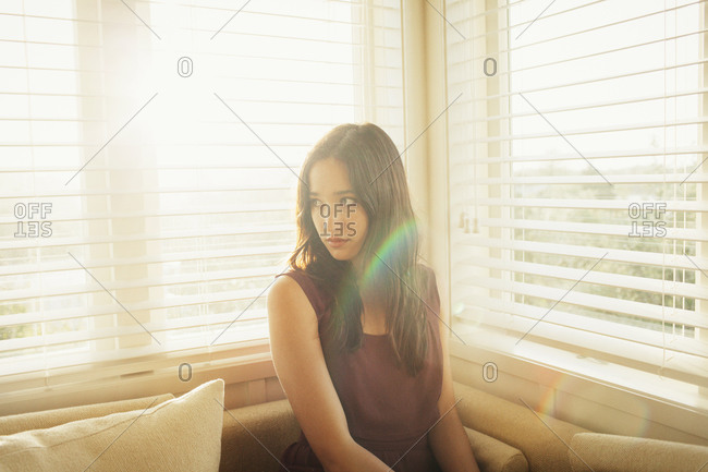 Woman sitting on a banquette seat in front of sunlit windows