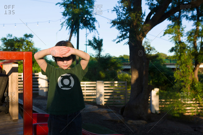 Young boy at playground blocking the sun from his eyes