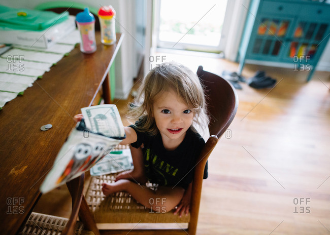 Toddler girl holding up play money