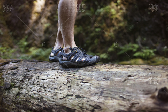 Man with hiking sandals standing on log