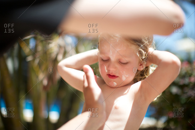 Parent applying sun lotion on girl\'s face