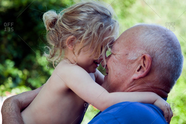 Small toddler girl and grandfather nose to nose
