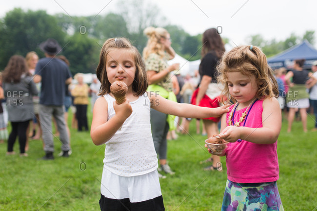 Two young girls enjoying chocolate ice cream at an outdoor fair