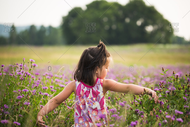 Young girl walking through field of purple flowers