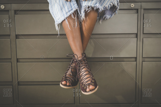 Fashionable worker sitting on file cabinets