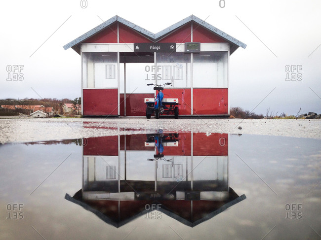 Ferry shelter with bike and trailer parked outside reflected water