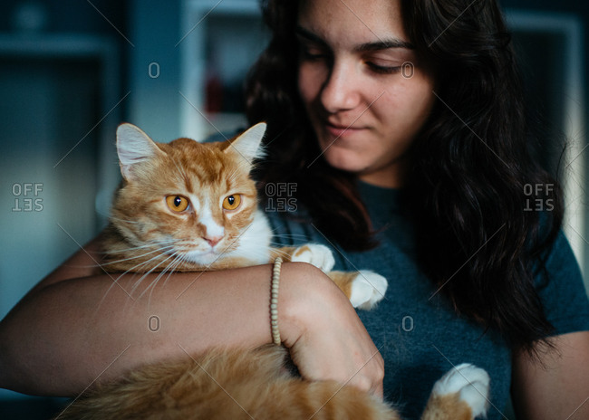 Teenage girl holding her pet orange cat
