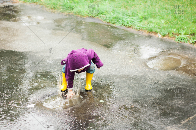 Girl playing in a rain puddle on concrete