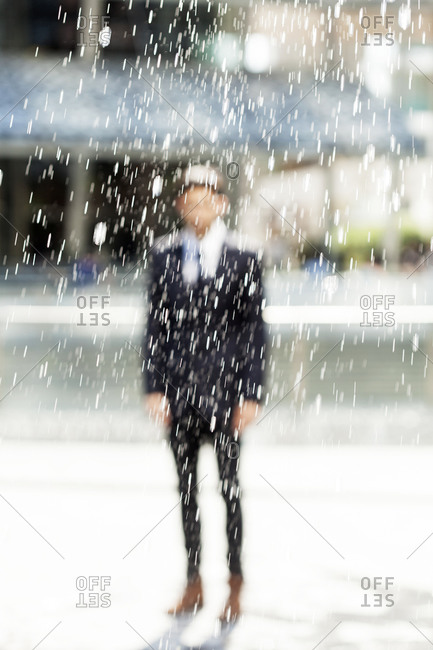 Portrait of blurred businessman standing behind a fountain