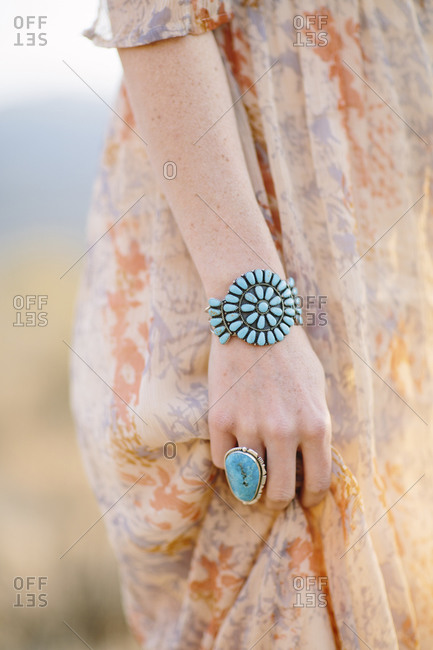 Woman wearing turquoise jewelry in a field
