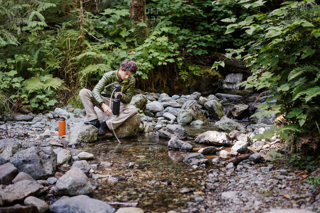 Boy using a water filtration system in a stream