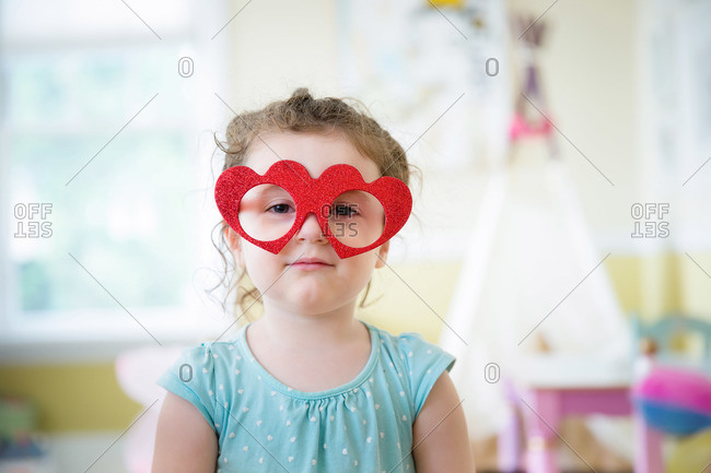 A girl wears heart shaped glasses