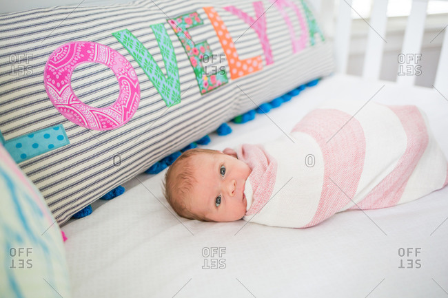 A swaddled newborn chews their blanket
