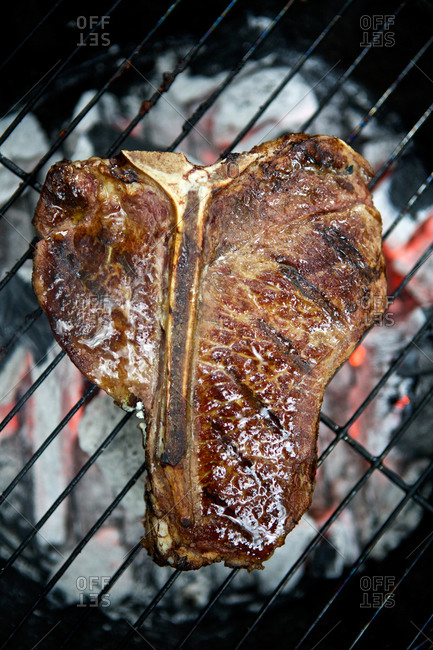 Juicy t-bone steak being cooked on grill