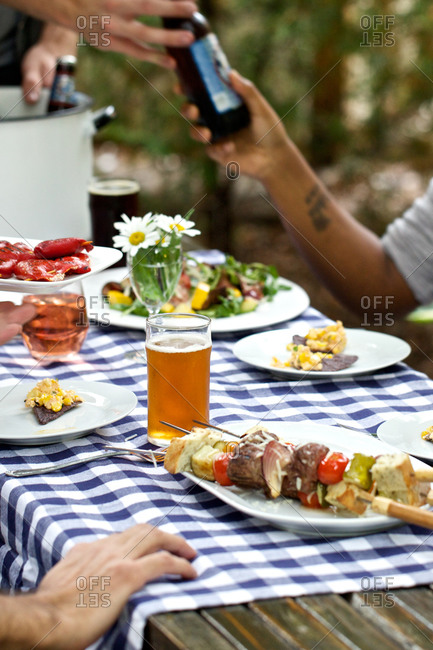 Group of friends sharing beer and food at a backyard barbecue