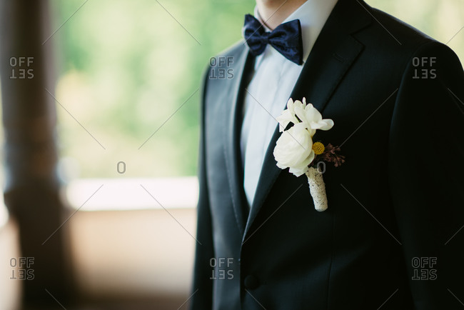 Groom standing at window wearing boutonniere