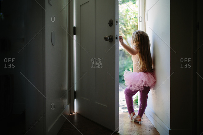 Young girl answering the door in tutu and leggings