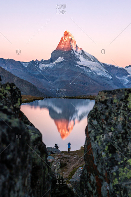 Hikers admire the Matterhorn reflected in the Stellisee at sunrise, Zermatt, Switzerland