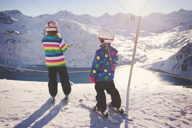 Two young girls overlook lake from top of ski slope
