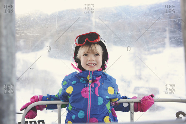 Smiling young girl leaning on railing of ski gondola
