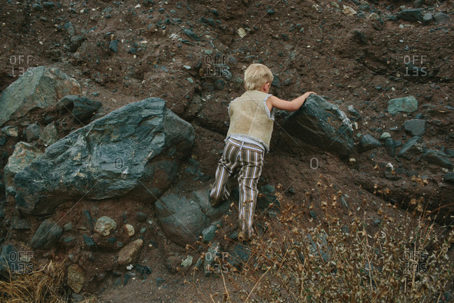 Little boy climbing on a rocky hill