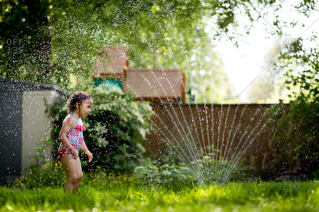 Little girl getting soaked in a sprinkler