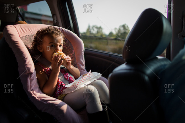 Girl eating a muffin riding in a car