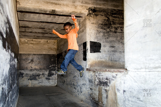 Boy leaping from ledge in abandoned building