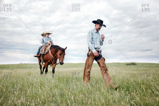 Cowboy walking ahead of his two sons on a horse