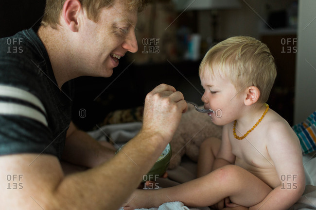 Father feeding his toddler son with a spoon
