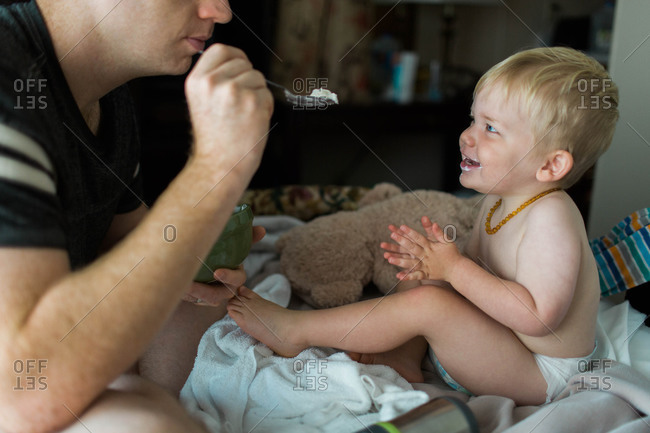 Toddler boy lovingly gazes at his father while being fed