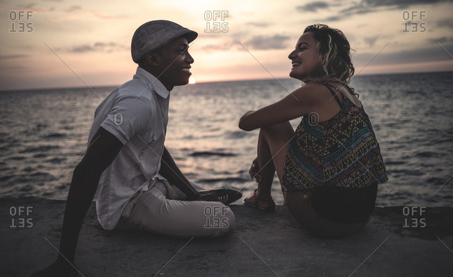 Couple sitting oceanfront at sunset in Cuba