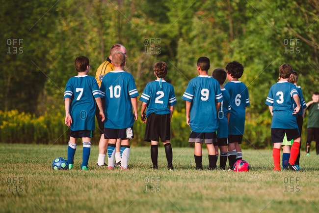 A boys soccer team gathers around their coach