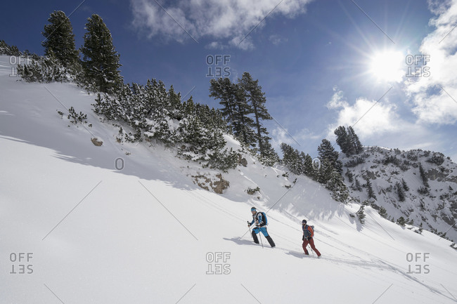 Skiers ascending a steep snow-covered slope