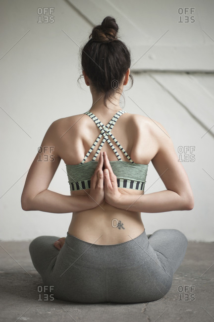Woman seated in a reverse prayer yoga pose