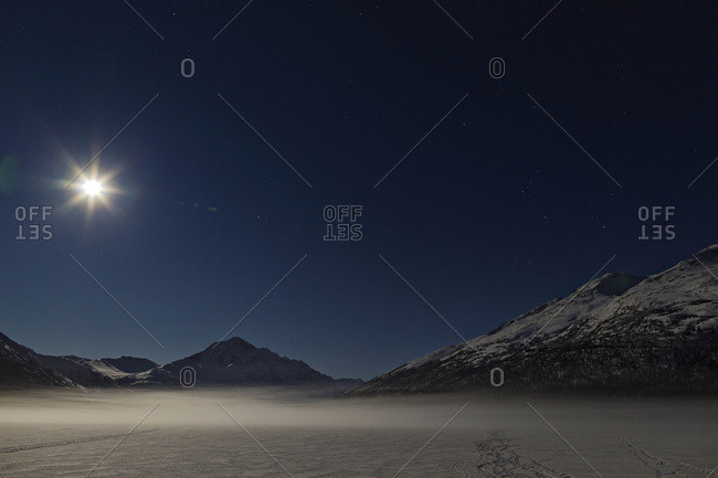 A Full Moon Illuminates Bold Peak And Ground Fog On Frozen Eklutna Lake In Chugach State Park In South-central Alaska, Winter