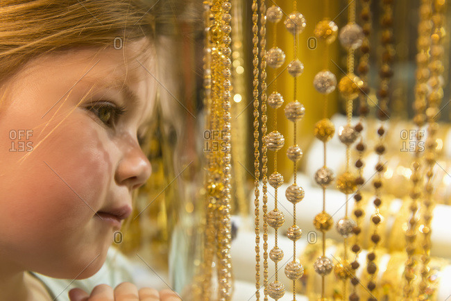 Young girl looking at gold jewelry for sale in window of shop in the gold souk, Dubai, United Arab Emirates