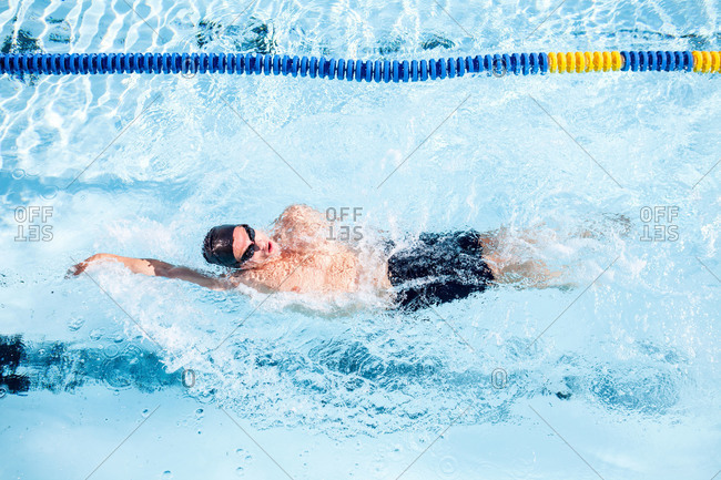 A swimmer does a backstroke through a pool