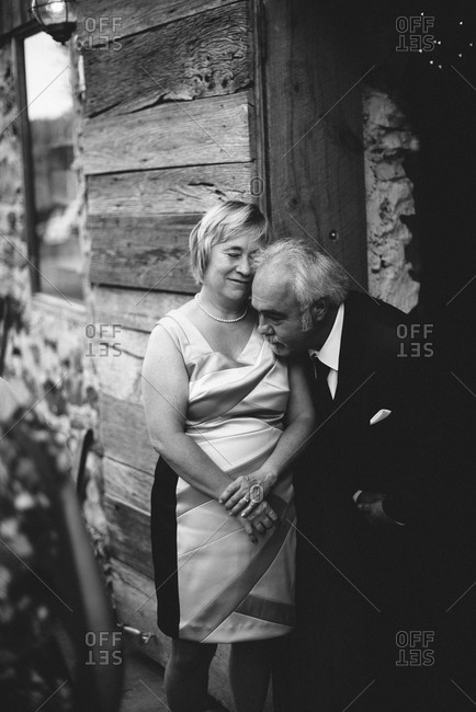 An older couple cuddles in a wooden doorway