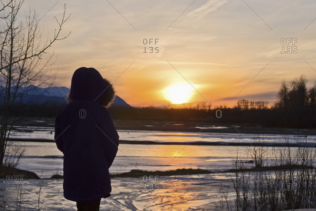 An Alaska native girl enjoying the sunset at Matanuska River in winter, Palmer, Alaska, United States of America
