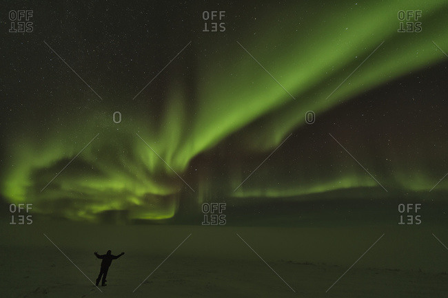 A person stands under the Northern Lights or Aurora Borealis, Old Crow, Yukon, Canada