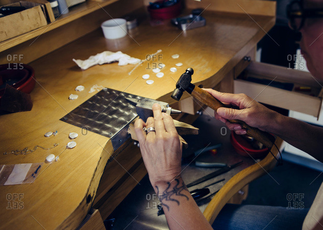 Woman hammering metal in a jewelry-making studio