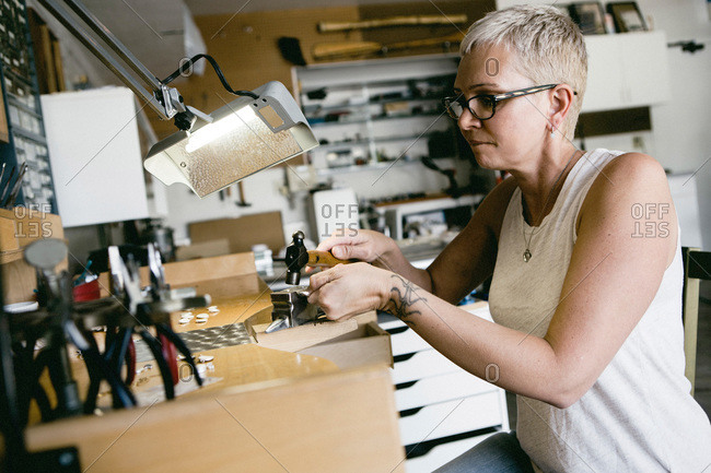 Woman hammering metal for a jewelry design