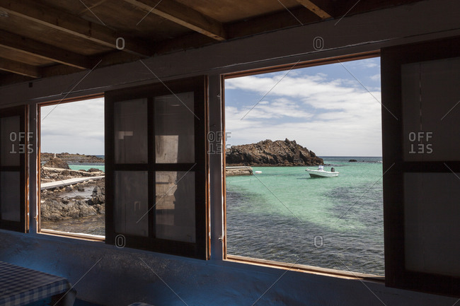 Window frames with clear blue ocean and a boat outside