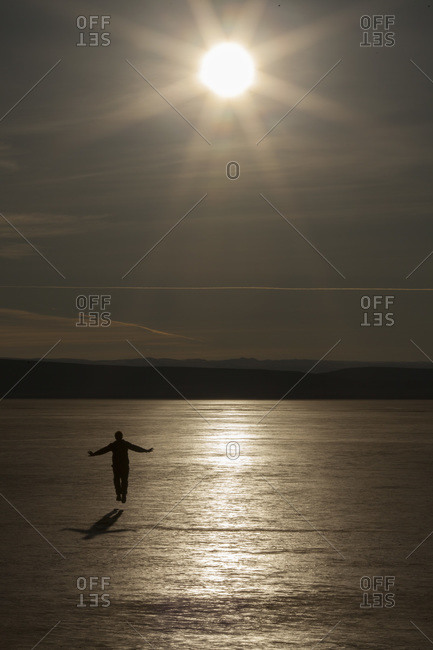 Silhouette of a man on a flat dry lake bed in the morning sun