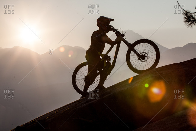 A mountain biker pushing his bike up a mountain in Canada