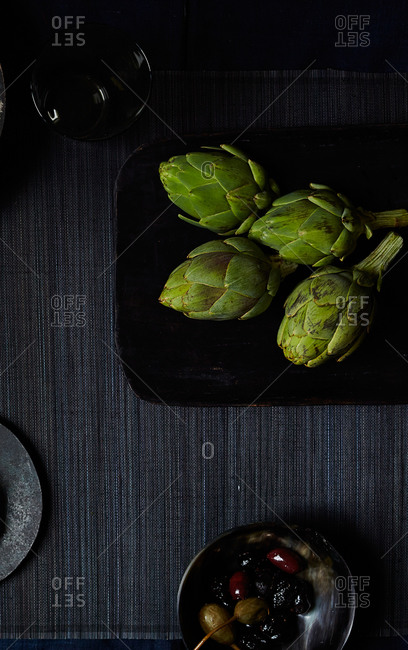 Overhead view table with tray of baby artichokes and dish of olives